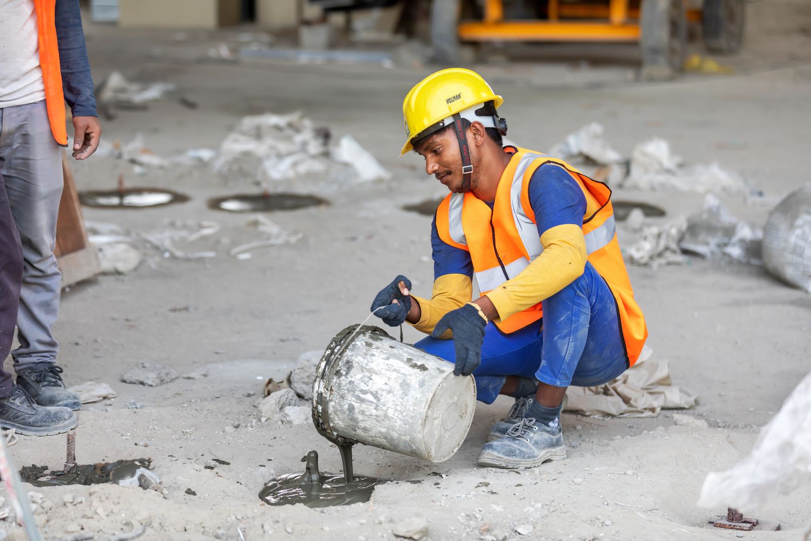 Illustrative construction worker in safety gear pouring concrete